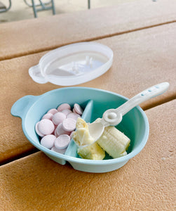 Cut banana in small pieced by using littoes feeding spoon. on a picnic bench in a park