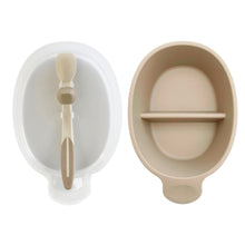 Load image into Gallery viewer, Translucent lid holds stay clean spoon is next to beige 6&quot; long sectioned bowl with a small handle.
